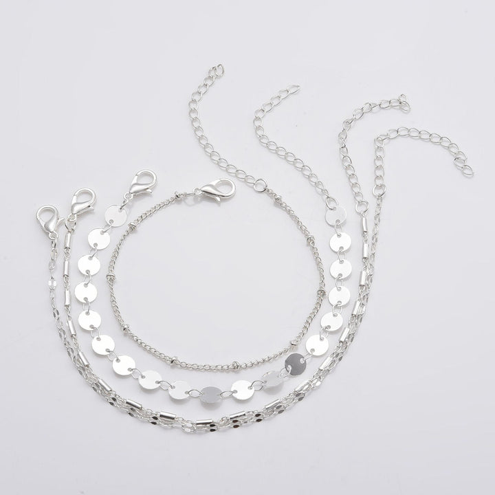 four Silver layered necklace on a light gray background