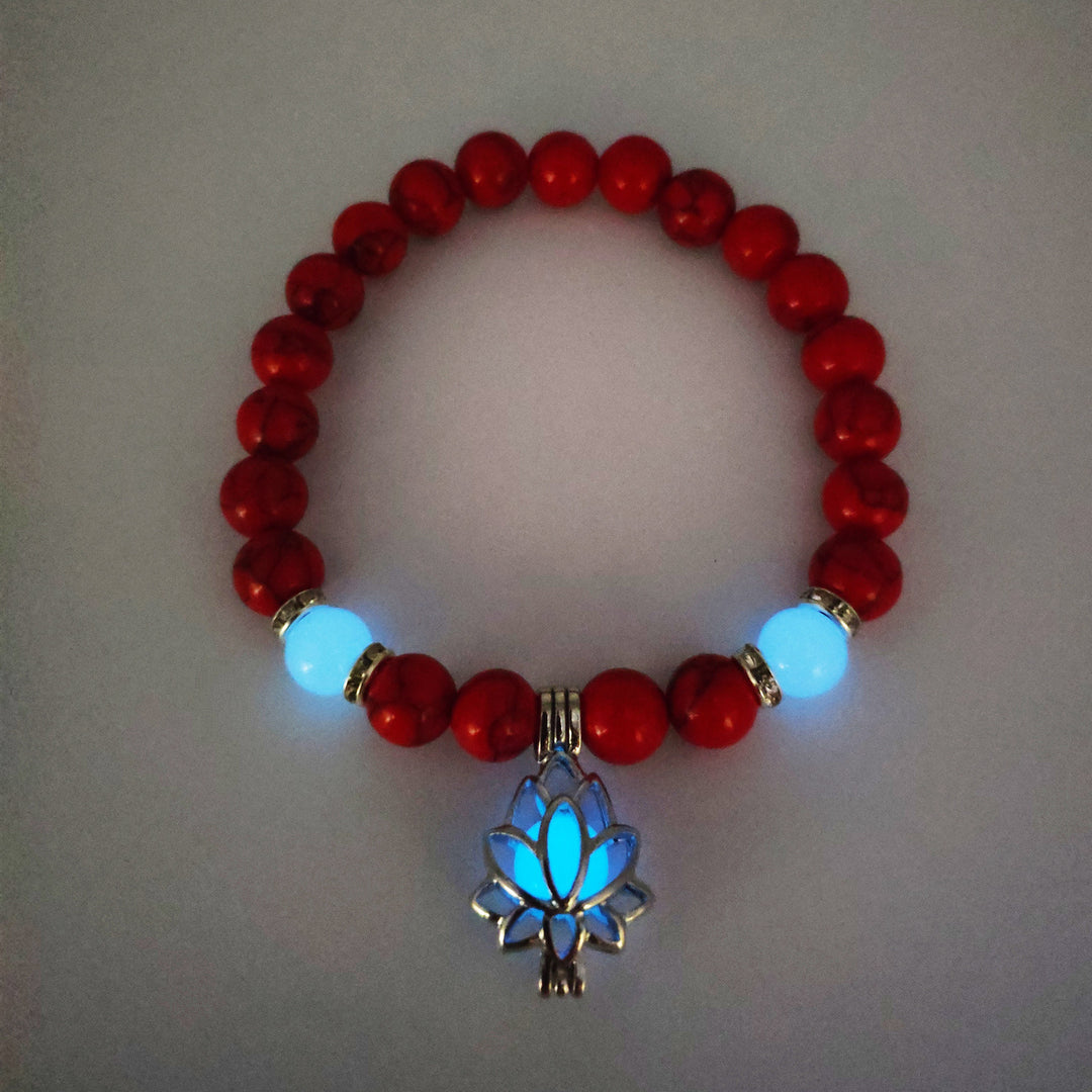 Red beaded bracelet with a glowing blue lotus flower charm on a light gray background
