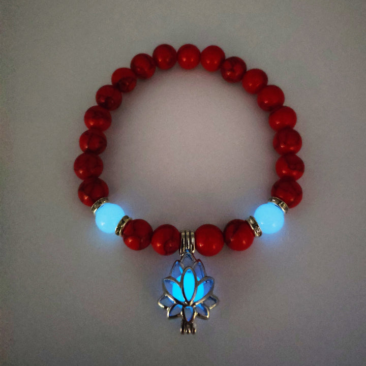 Red beaded bracelet with a glowing blue lotus flower charm on a light gray background