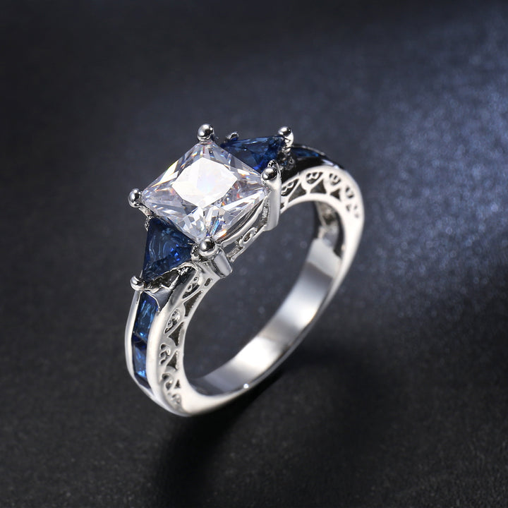 Silver ring with a large central zircon and smaller blue stones on a dark background