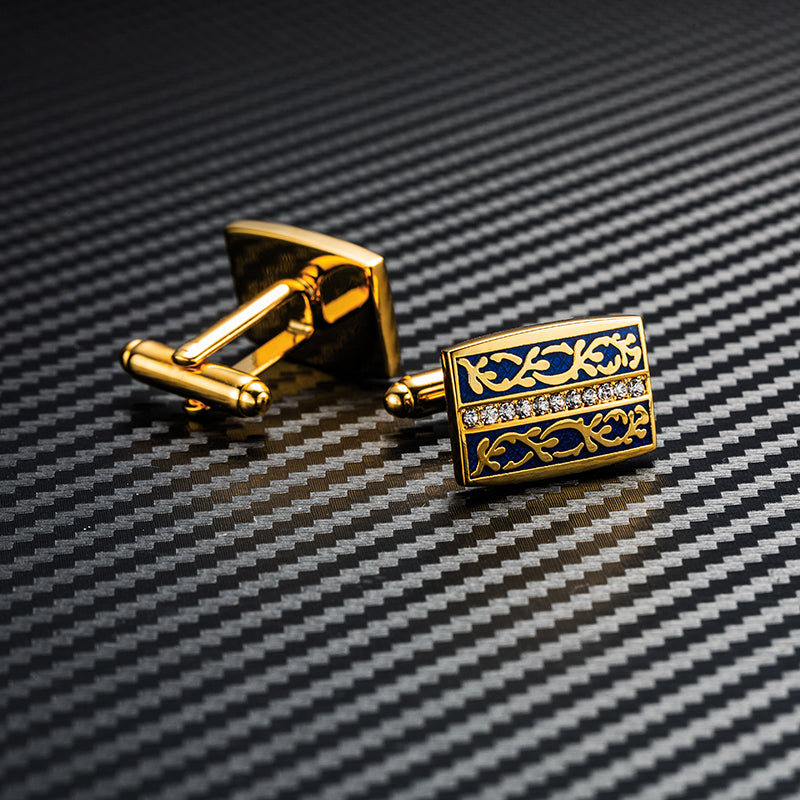Gold and blue cufflinks on a white and black sheet