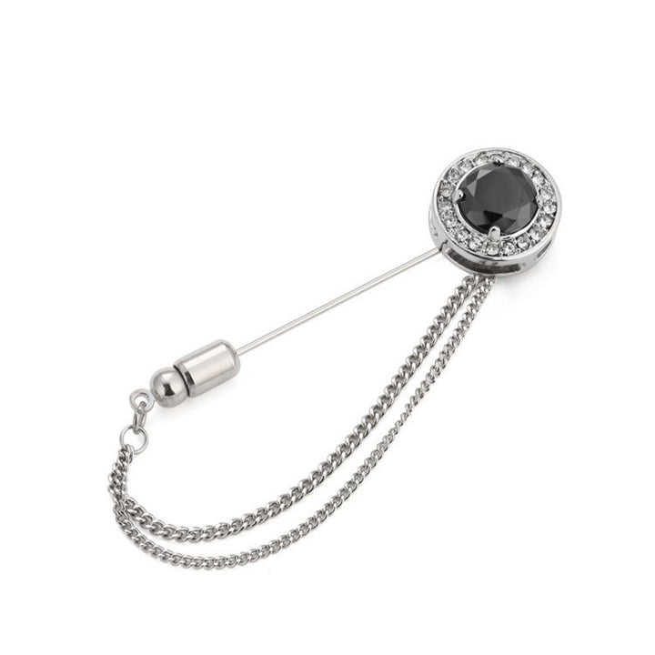 Silver brooch with black gemstone and chain on a white background