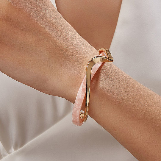 Gold bracelet on a wrist with a neutral background