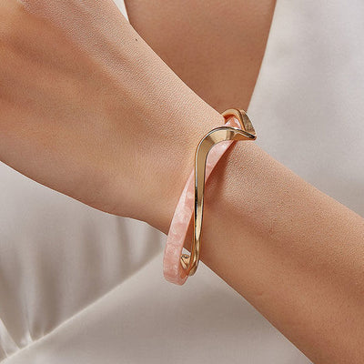 Gold bracelet on a wrist with a neutral background