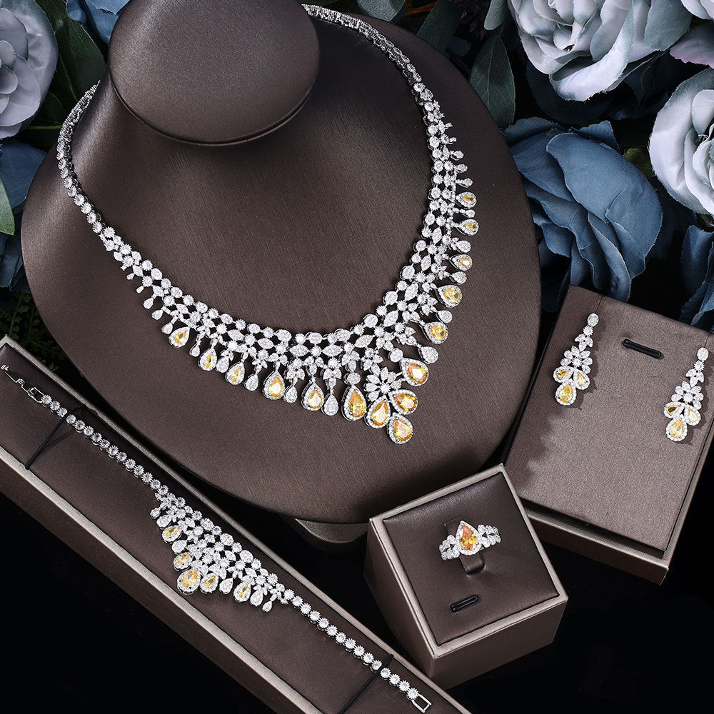 yellow zircon bridal Jewelry set including necklace, earrings, bracelet and ring on a brown stand with flowers in the background.