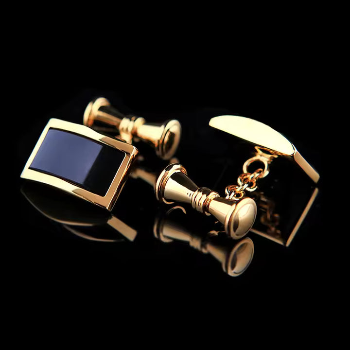 Gold cufflinks with a blue stone on a black background