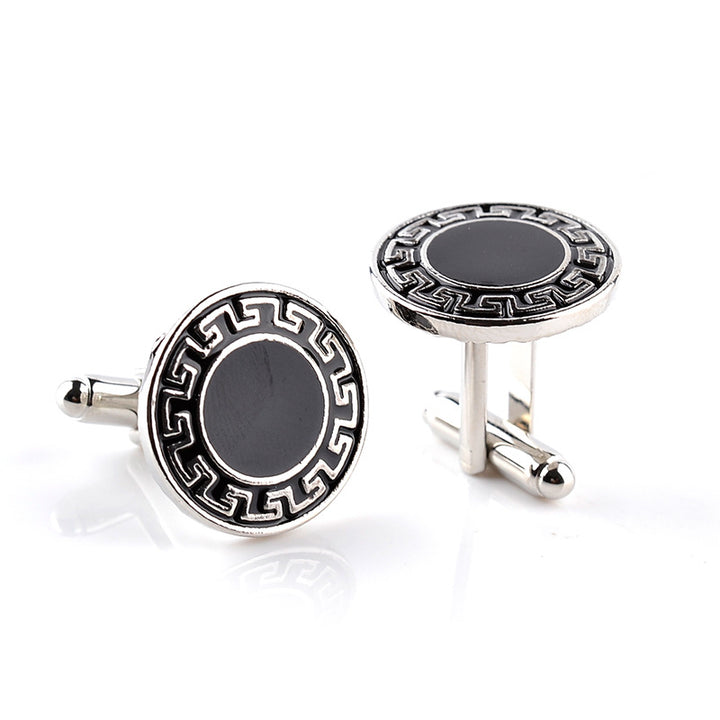 Pair of silver cufflinks with black circular design on a white background