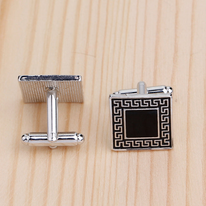 Silver cufflinks with black center on a wooden surface