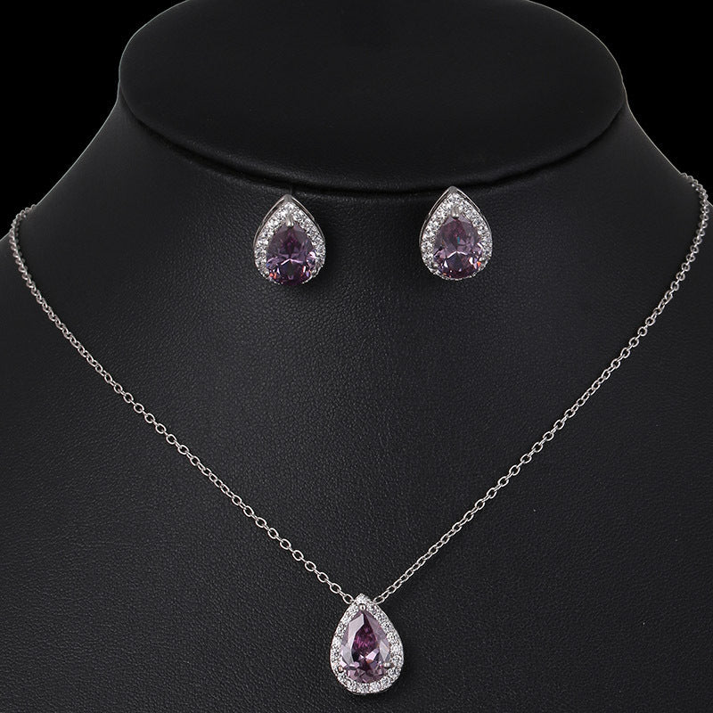 Jewelry set with necklace and earrings featuring purple teardrop stones on a black mannequin.