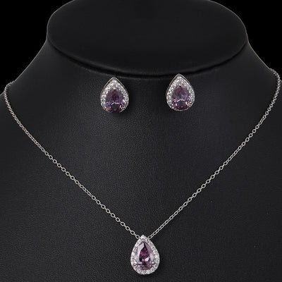 Jewelry set with necklace and earrings featuring purple teardrop stones on a black mannequin.