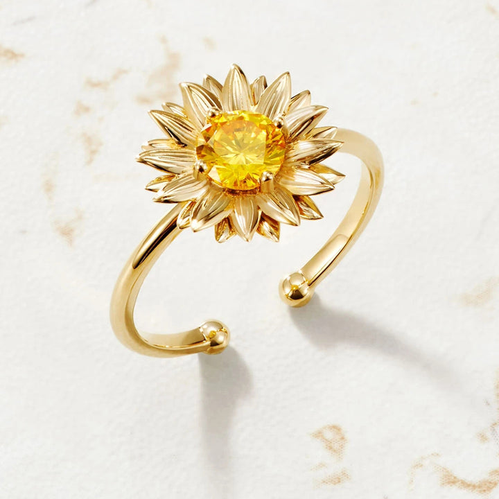Gold sunflower-shaped bracelet with a yellow gemstone on a light background