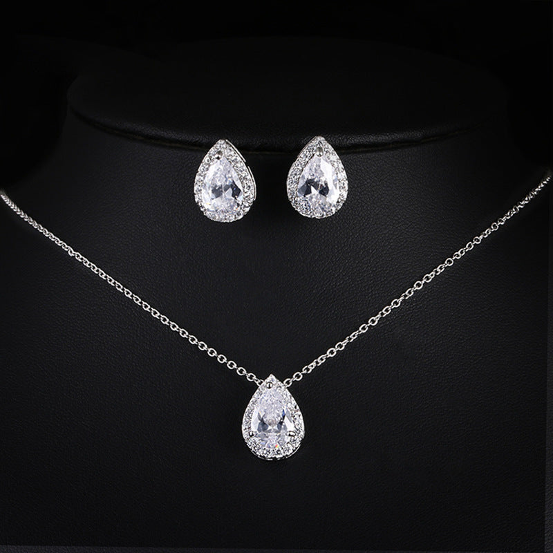 Jewelry set with teardrop-shaped necklace, pendant, and earrings on a black background