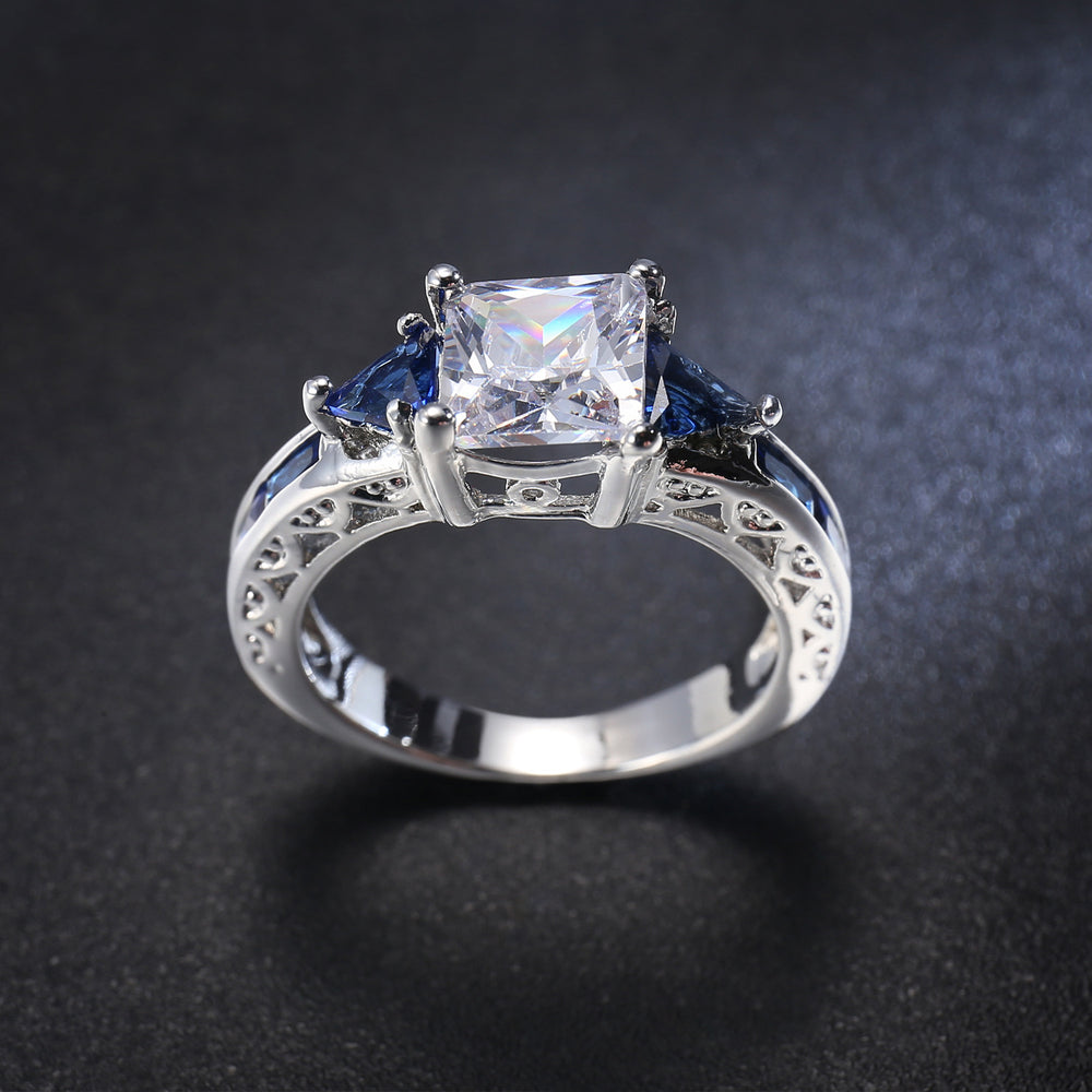 Silver ring with a central zircon and blue gemstones on a dark background