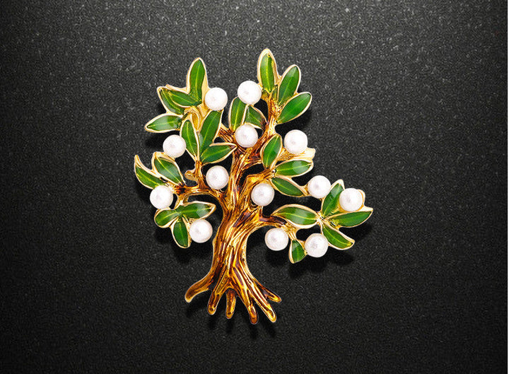 Tree-shaped brooch with green leaves and white berries on a black background