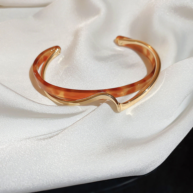 Gold and tortoiseshell bangle on a white fabric background