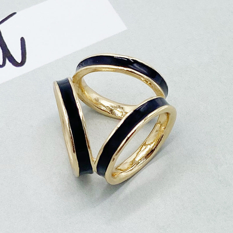 Gold ring with black enamel stripes on a light gray background