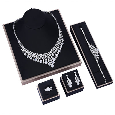 white zircon bridal Jewelry set including necklace, bracelet, earrings, and ring on black display stands.