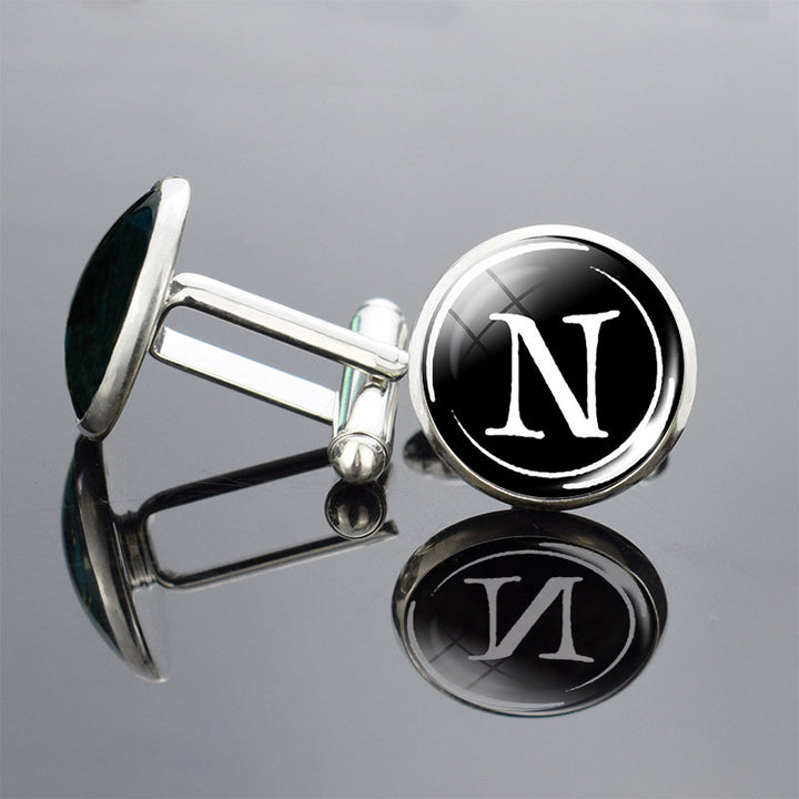 Cufflinks with a black round emblem featuring the letter &