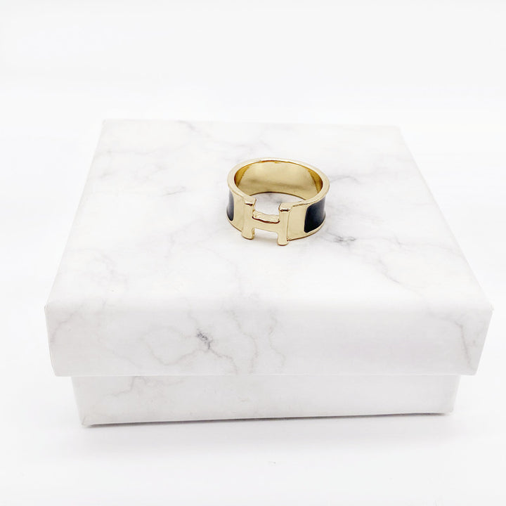 Gold ring with a black center on a white marble surface