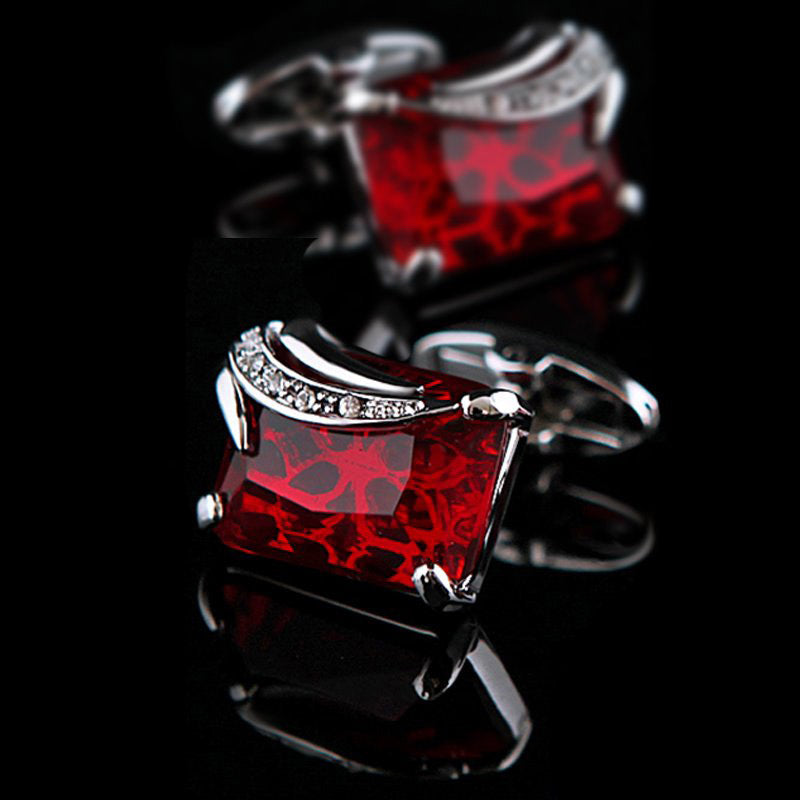 Red square cufflinks with silver accents on a black background
