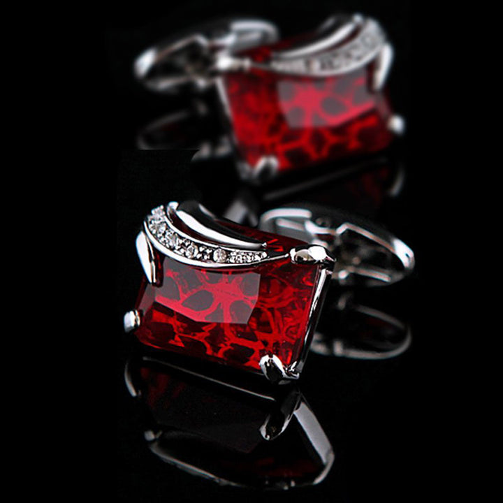 Red square cufflinks with silver accents on a black background