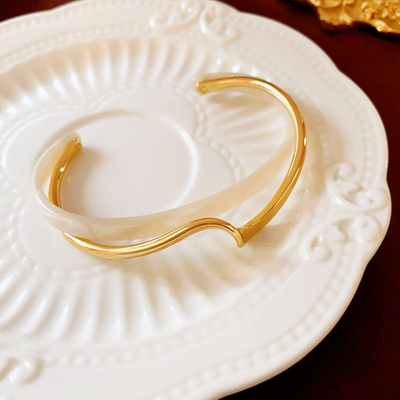 Gold bracelet on a white ceramic dish
