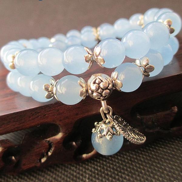 Light blue beaded bracelet with gold charms on a wooden surface