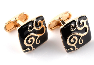 Black and gold cufflinks with intricate designs on a white background