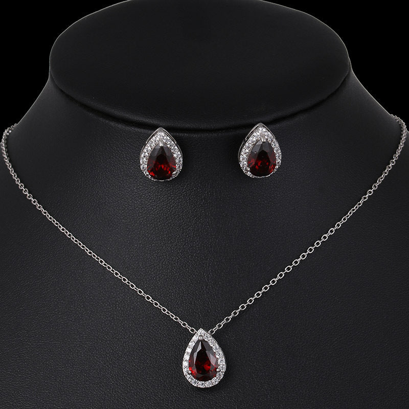 Jewelry set with teardrop-shaped red gemstones on a black mannequin.