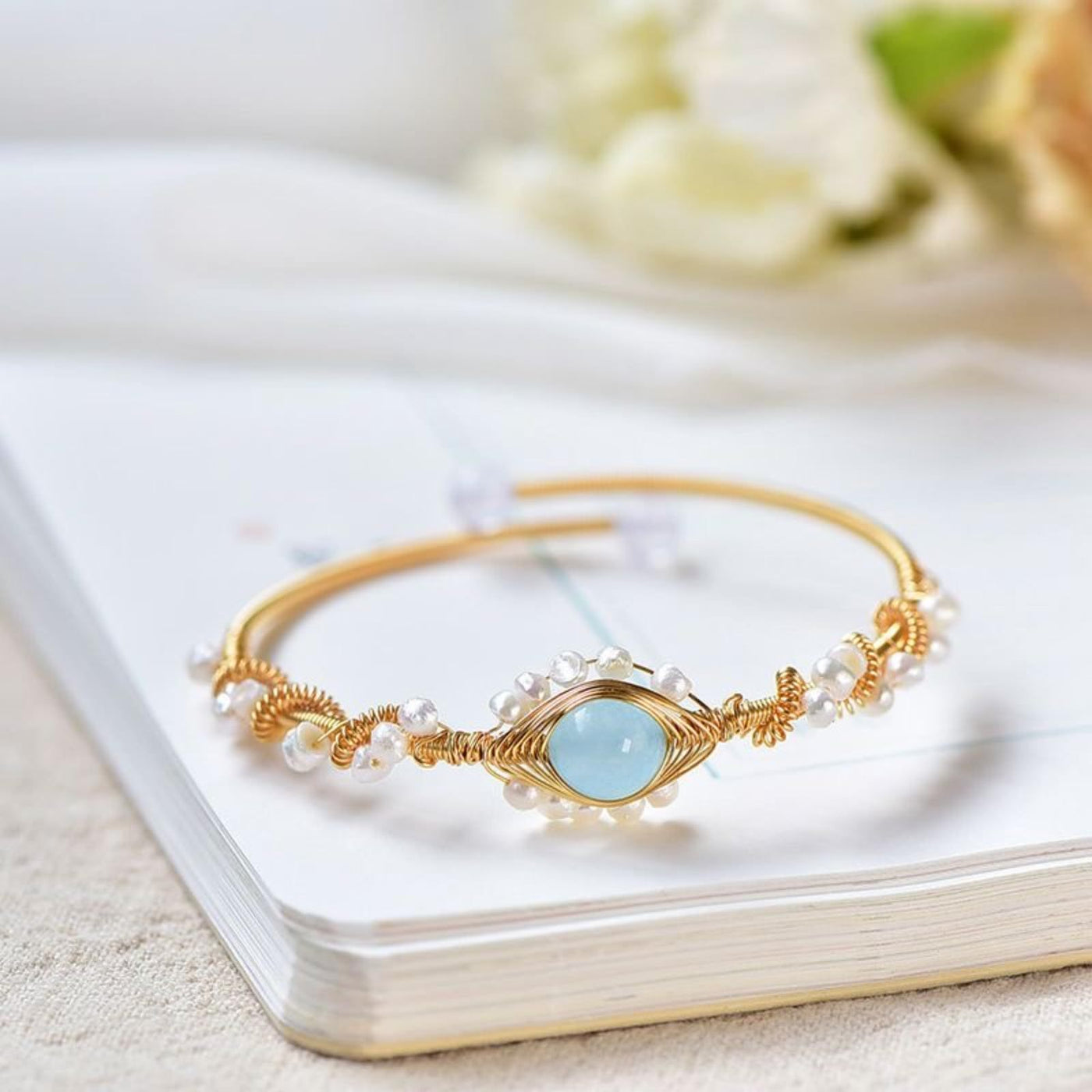 central view of a Gold bracelet with a blue gemstone on a white surface