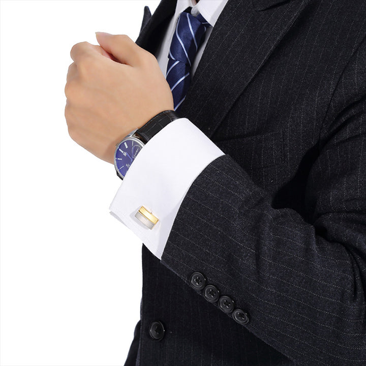 Close-up of a person wearing a dark suit with a white shirt and blue tie, focusing on the cufflink.