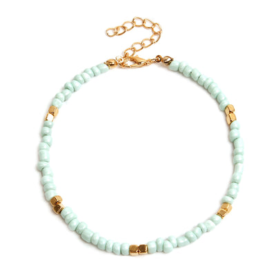 Mint green beaded anklet with gold accents on a white background