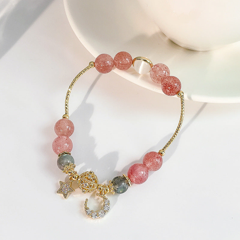 Bracelet with pink beads and gold charms on a white surface