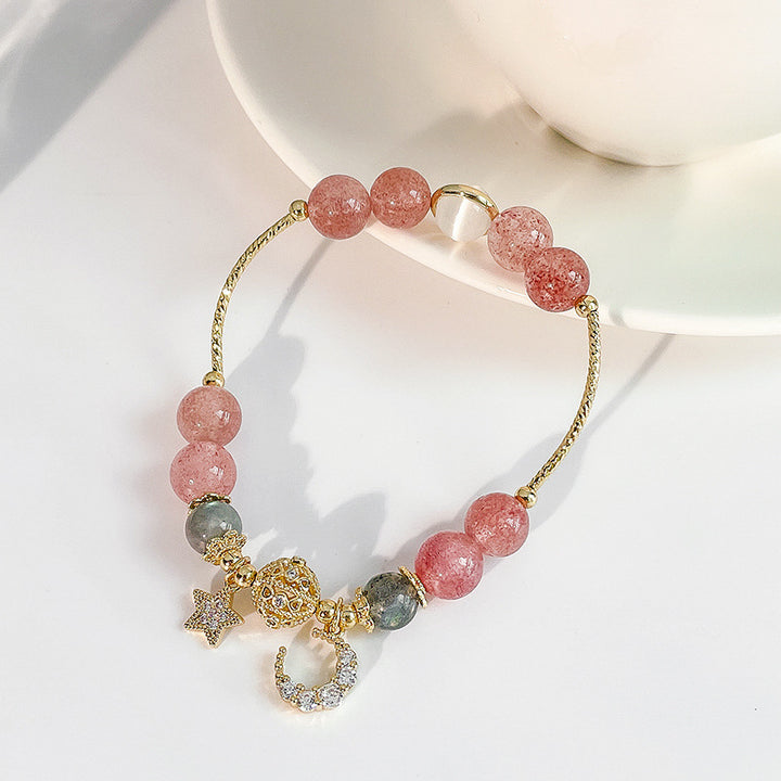 Bracelet with pink beads and gold charms on a white surface