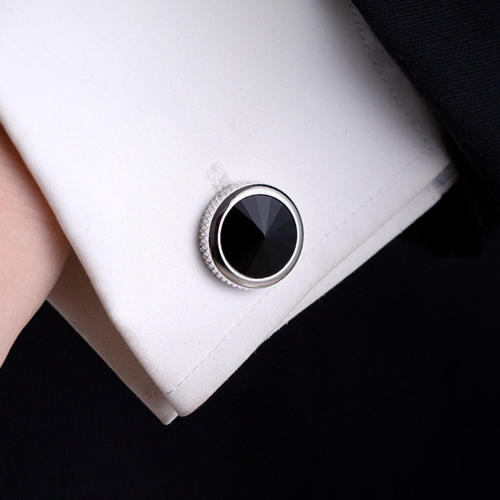 Close-up of a cufflink on a white shirt against a black background