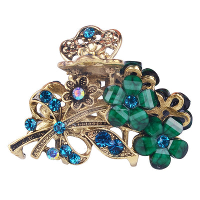 Decorative hair clip with gold, green, and blue gemstones on a white background
