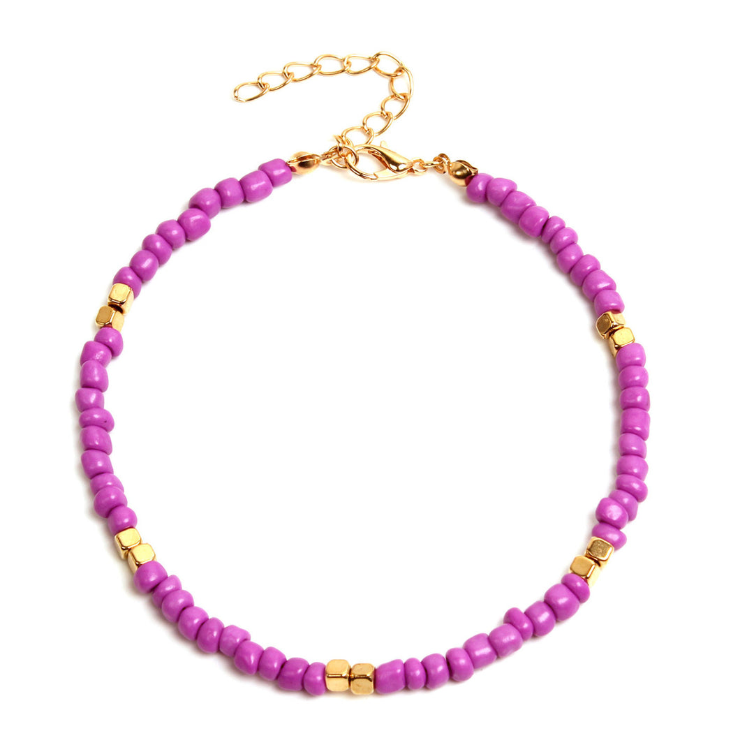 Pink beaded anklet with gold accents on a white background