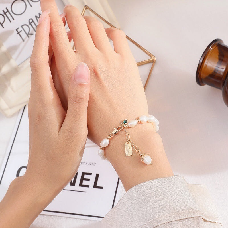 Close-up of hands wearing a pearl bracelet on a light background