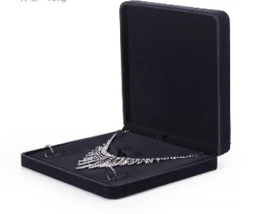 Black jewelry box with a silver necklace inside on a white background