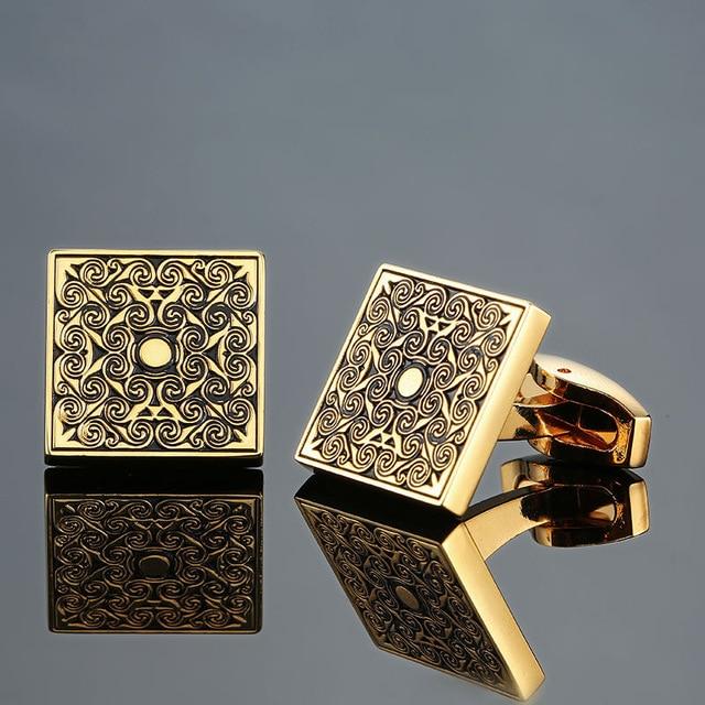 Gold square cufflinks with intricate patterns on a gray background