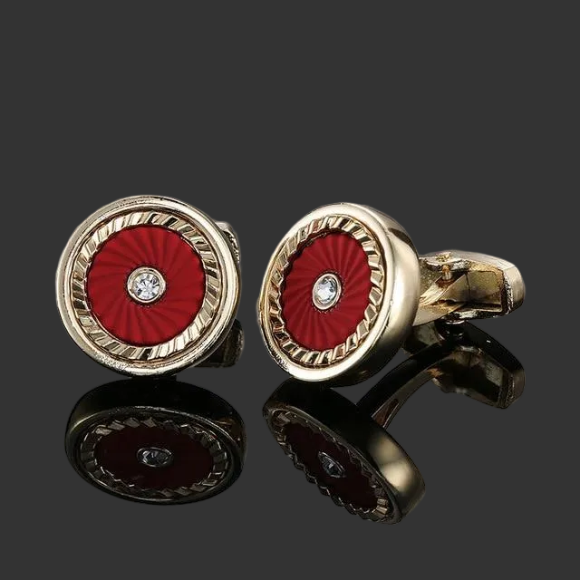 Gold cufflinks with red center and diamond-like stone on a black background