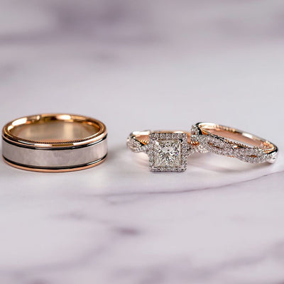 three wedding rings, one gold and two with a diamond, on a marble surface.
