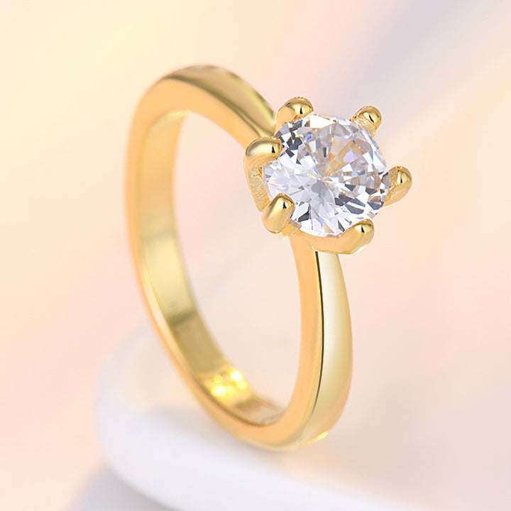 Gold ring with a clear gemstone on a soft gradient background