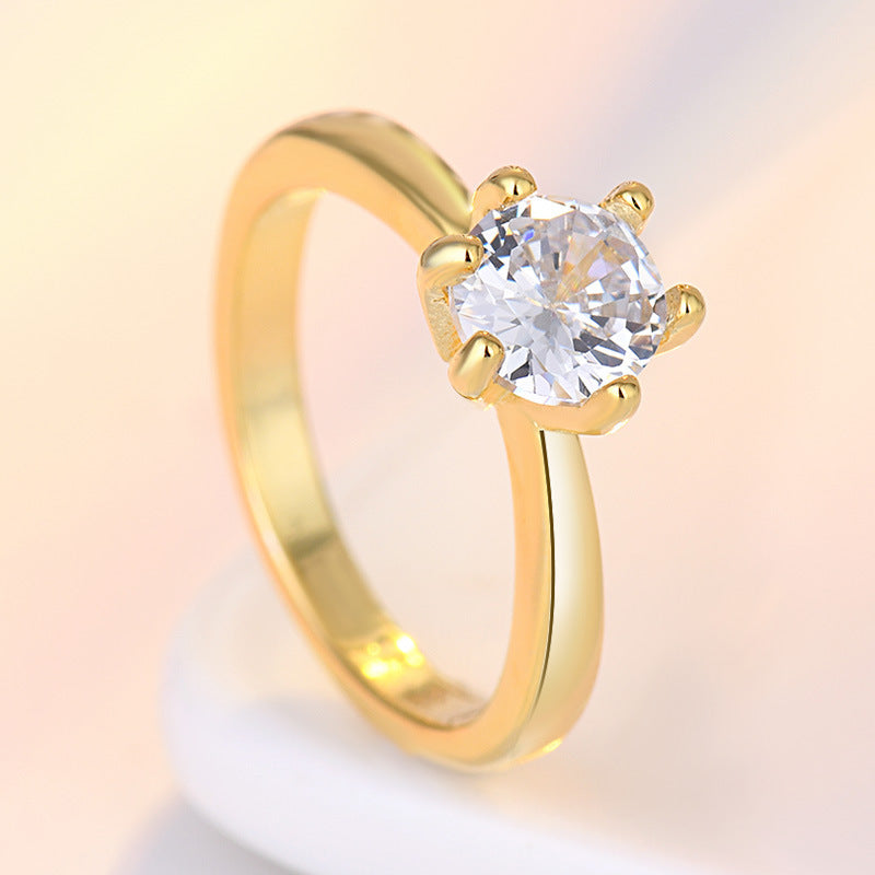 Gold ring with a clear gemstone on a soft gradient background