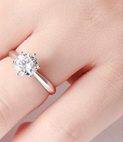 Silver ring with a large zircon  on a finger against a neutral background