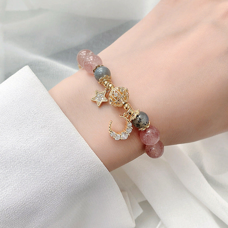 Bracelet with star and moon charms on a wrist against a white background