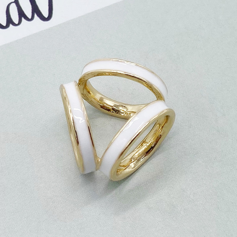 Two gold rings with white enamel on a light gray background