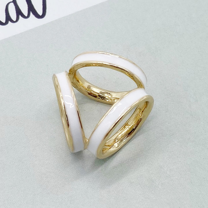 Two gold rings with white enamel on a light gray background