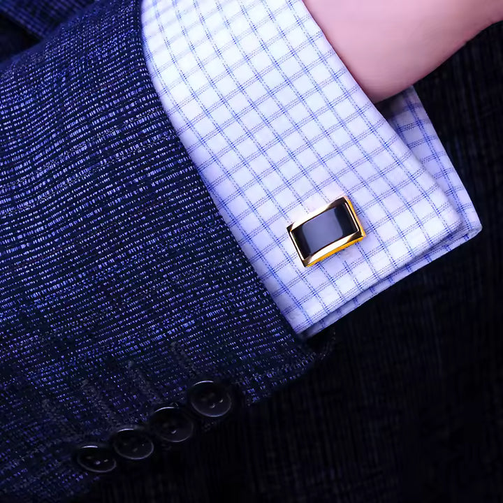 Close-up of a cufflink on a checkered shirt against a dark background