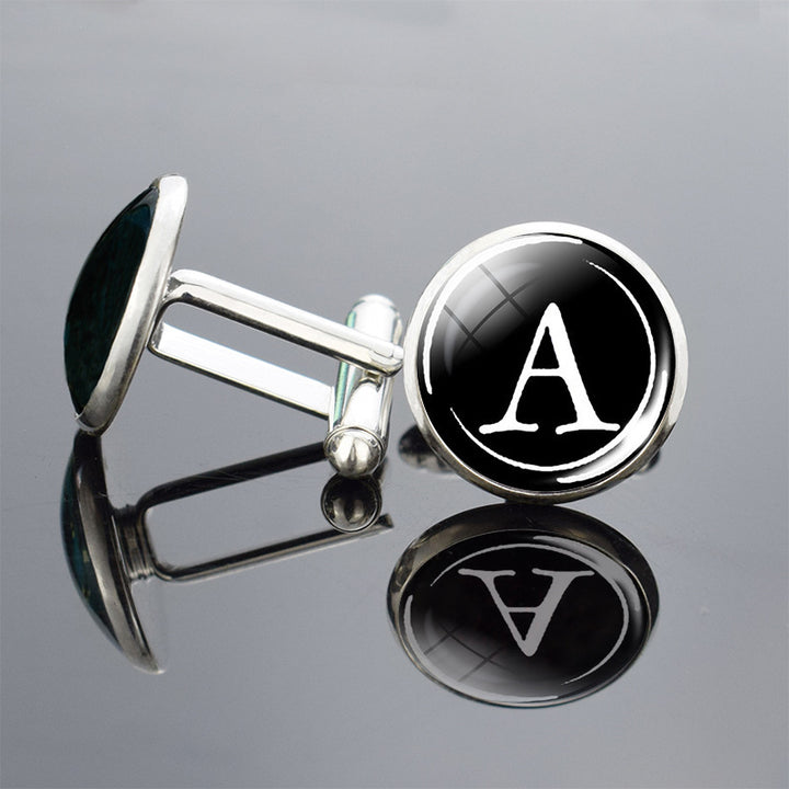 Cufflinks with a black round emblem featuring the letter &